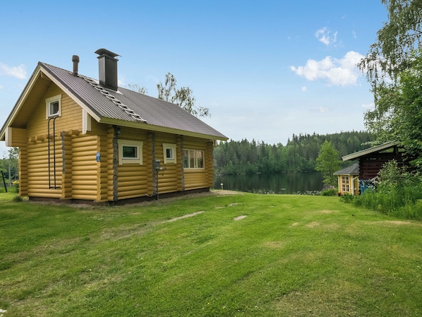 A log cabin with a metal roof, a chimney, and a small porch.