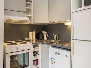 Una cucina compatta con fornello, forno, lavastoviglie e lavello.