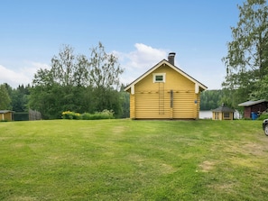 A yellow log cabin with a chimney, surrounded by a grassy yard and trees. - Ahvenranta by Interhome (Tuusniemi)