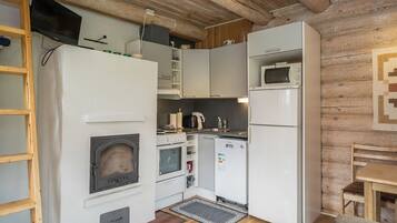 Una cocina compacta con estufa de leña, microondas y refrigerador.