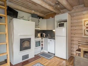 A compact kitchen with a wood stove, a microwave, and a refrigerator. - Ahvenranta by Interhome (Tuusniemi)