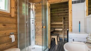 Een houten badkamer met een douchecabine van glas, een toilet en een wastafel.