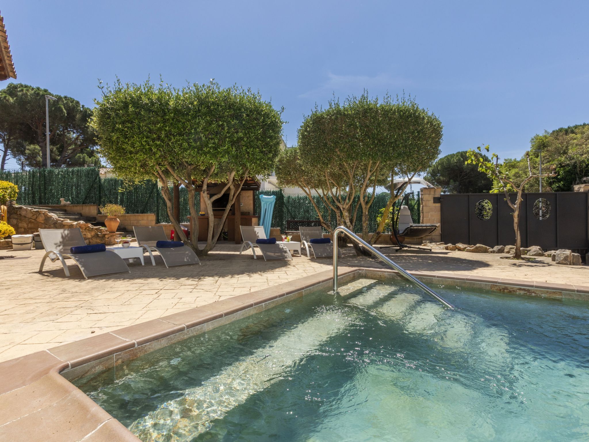 A swimming pool with lounge chairs and a pergola.