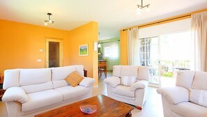A living room with two white sofas, a wooden coffee table, and a dining area in the background. - Vacation home Marina by Interhome (Vidreres)