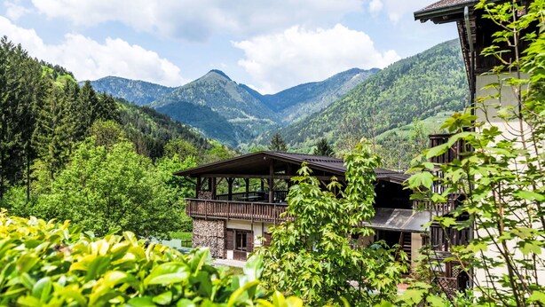 A chalet-style building with a balcony, surrounded by lush greenery and mountains in the background. - Lembondel by Interhome (Tiarno di Sotto)
