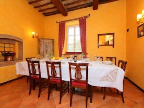 A dining room with a long table set for six, surrounded by wooden chairs.