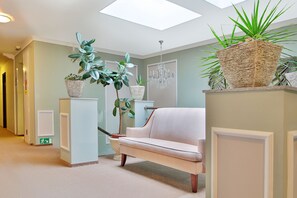 A hallway with a light-colored sofa, a chandelier, and potted plants. - Sun Palace Wellness Hotel Marianske Lazne (Marianske Lazne)