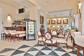 A hotel lobby with a bar area, seating arrangements, and a patterned floor. - Sun Palace Wellness Hotel Marianske Lazne (Marianske Lazne)