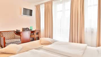 A hotel room with a bed, a desk, a chair, and a TV.