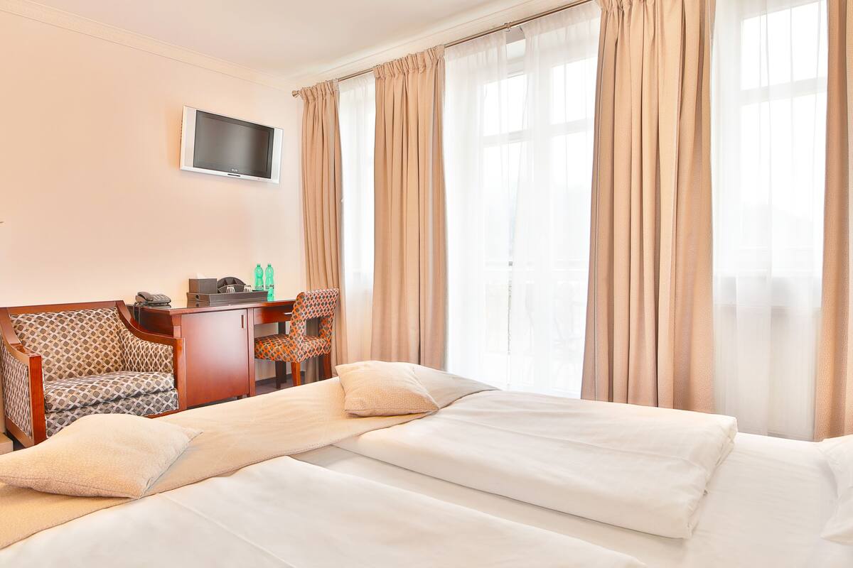 Ein Hotelzimmer mit Bett, Schreibtisch, Stuhl und Fernseher.