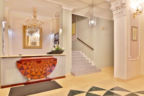 A reception area with a decorative console, a staircase, and a chandelier. - Sun Palace Wellness Hotel Marianske Lazne (Marianske Lazne)