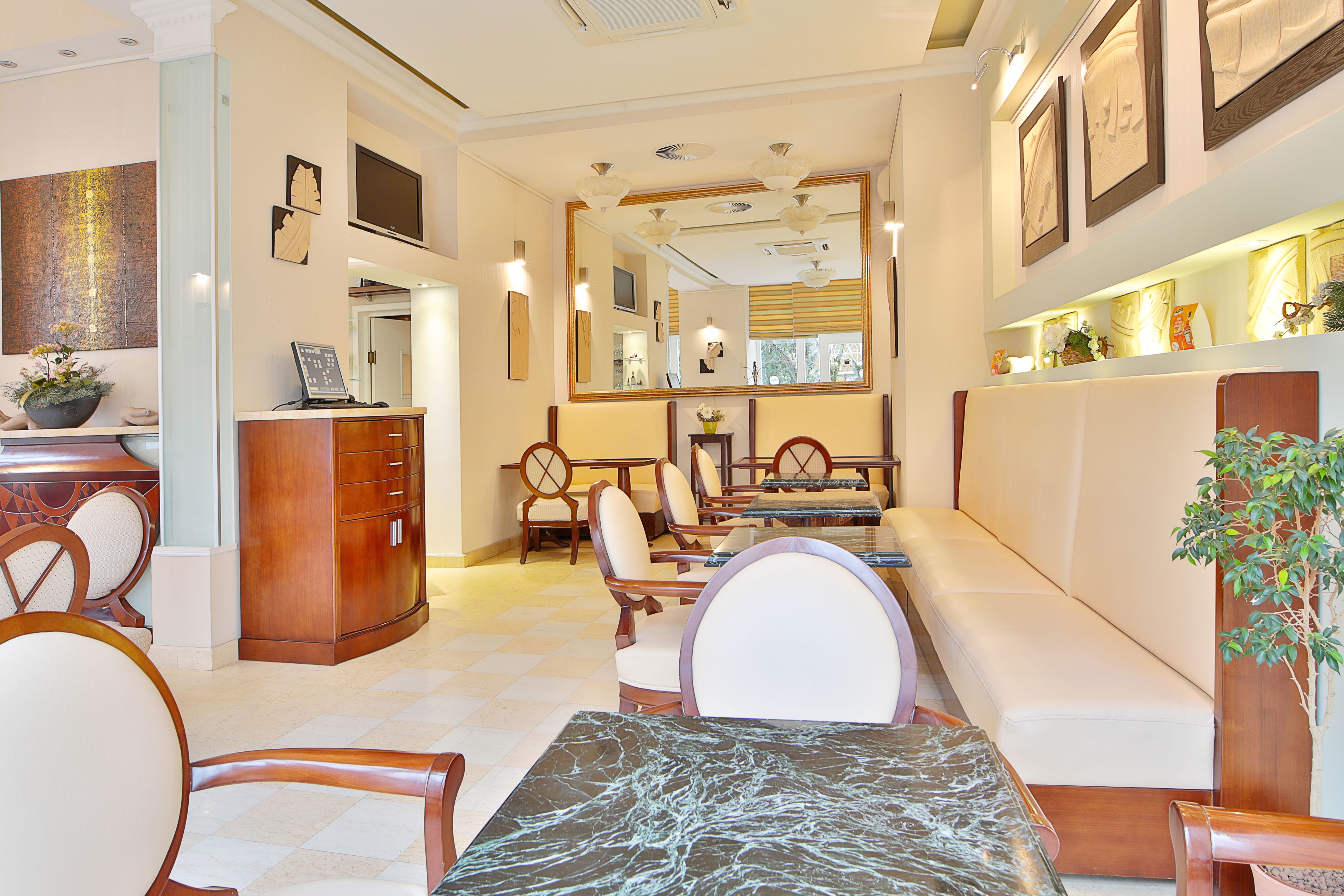 A hotel lobby with a reception desk, seating area, and a large mirror.