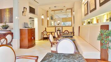 A hotel lobby with a reception desk, seating area, and a large mirror.