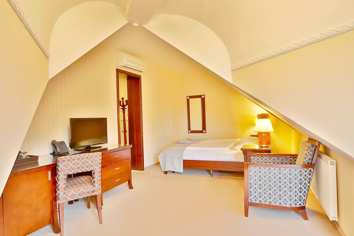 Ein Schlafzimmer mit Bett, Schreibtisch, Stuhl, Fernseher und Lampe.