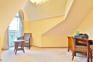 A room with a sloped ceiling, a balcony with a wrought iron railing, two wooden chairs with patterned upholstery, and a small round table. - Sun Palace Wellness Hotel Marianske Lazne (Marianske Lazne)