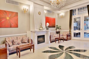 A spacious lobby with a fireplace, floral sofas, a large abstract painting, and a chandelier. - Sun Palace Wellness Hotel Marianske Lazne (Marianske Lazne)