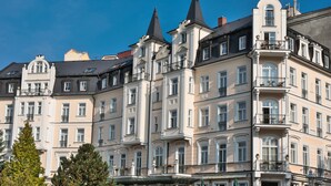 A multi-story building with a classic architectural style, featuring balconies and large windows. - Sun Palace Wellness Hotel Marianske Lazne (Marianske Lazne)