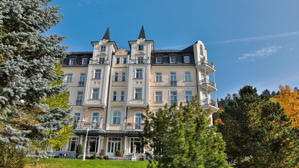 A large, multi-story building with a symmetrical facade, multiple balconies, and a central entrance with steps.