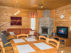 A cozy cabin interior with a fireplace, wooden furniture, and a television. - Nuottiukko by Interhome (Kittilä)