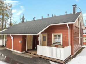 A wooden cabin with a porch, a door, and a window.