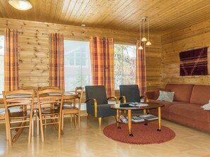 A wooden interior with a dining area, two armchairs, a sofa, and a small table with a rug. - Nuottiukko by Interhome (Kittilä)