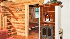 Een gezellig chaletinterieur met een houten trap, een open haard en een bed.