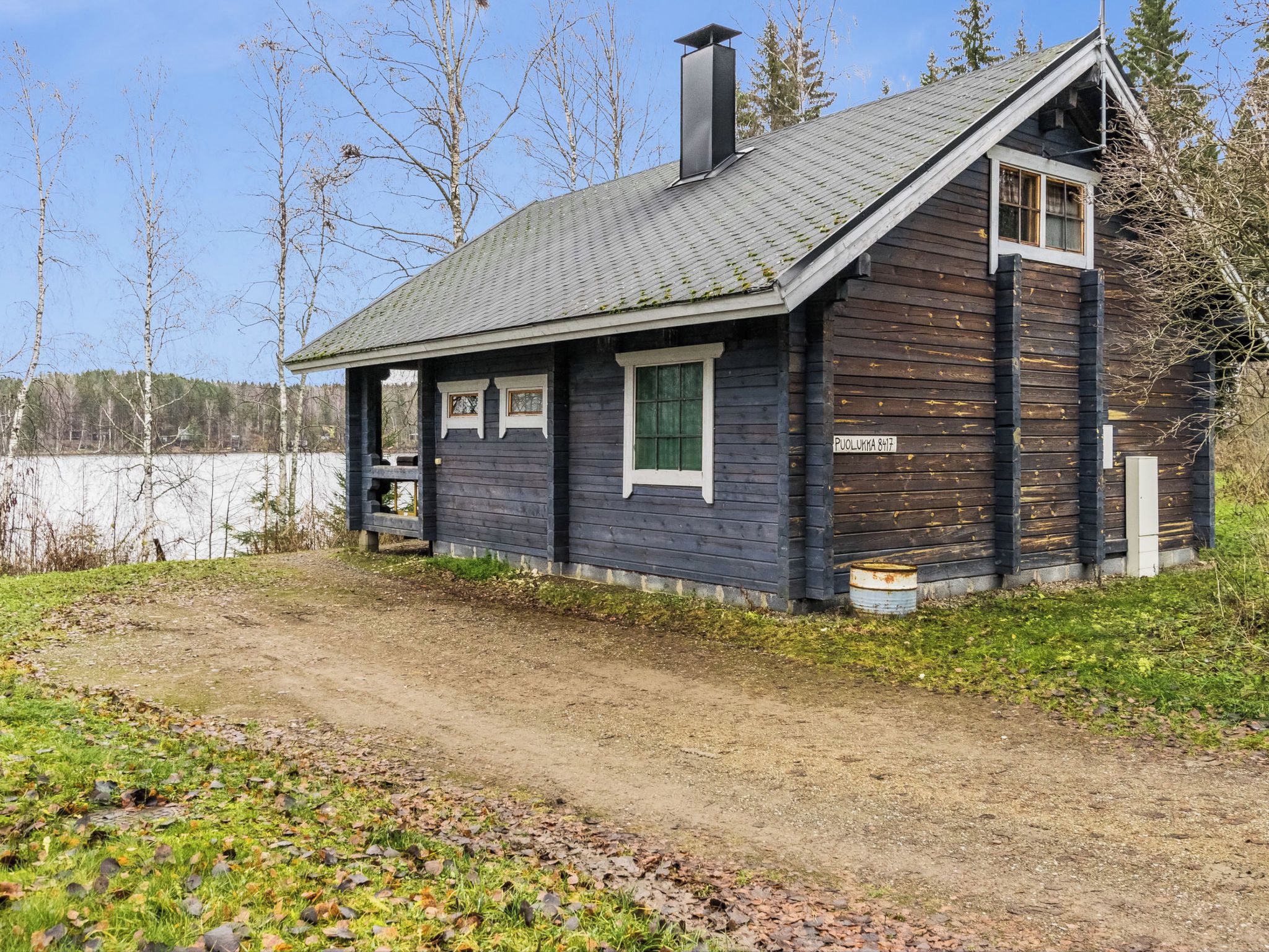 A wooden cabin with a sloped roof, a chimney, and a small porch.