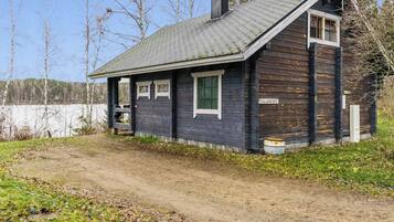A wooden cabin with a sloped roof, a chimney, and a small porch.