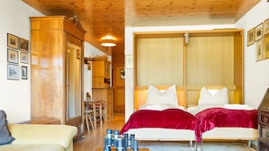 A cozy room with a bed, a sofa, and a table with binoculars and a magazine.