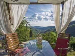 Relax in a serene outdoor space with a stunning mountain view, featuring a glass table and comfortable seating.