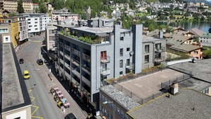 A modern hotel with a rooftop terrace, a parking area, and a view of a lake and mountains. - Chesa Sül Muot by Interhome (St. Moritz)