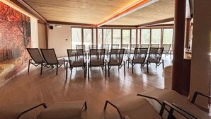 Un salón de conferencias con techo de madera, ventanas amplias y un mural en la pared.