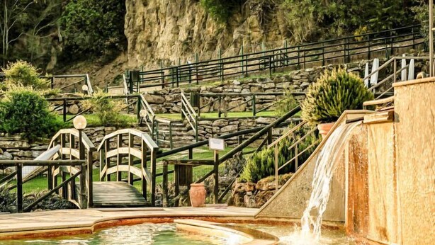 Una fuente de agua con un pequeño puente y escaleras que conducen a una plataforma elevada.