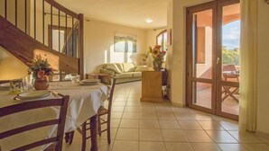 Un comedor con una mesa de madera dispuesta para dos personas, un sofá y un balcón con vistas.