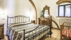 Ein Schlafzimmer mit zwei Betten, einem Schminktisch, einem Spiegel und einem Babybett.