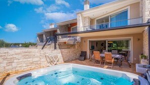 A modern house with a hot tub, outdoor seating, and a stone wall. - Sv. Ivan 1 by Interhome (Umag)