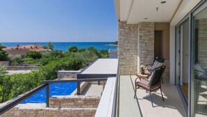 A balcony with a view of the sea, a pool, and a chair. - Sv. Ivan 1 by Interhome (Umag)