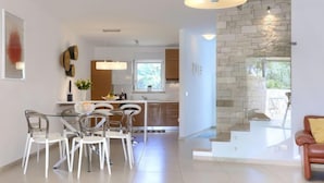 A modern kitchen with a stone accent wall, a dining area with clear chairs, and a leather sofa. - Sv. Ivan 1 by Interhome (Umag)