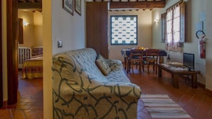 A cozy living room with a patterned sofa, a dining table with chairs, and a window with a checkered pattern. - Leonardo - Borgo Fontana by Interhome (Vinci)