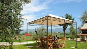 A covered outdoor dining area with a table and chairs, surrounded by greenery and a view of the countryside. - Leonardo - Borgo Fontana by Interhome (Vinci)