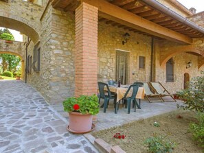 A stone building with a covered patio, outdoor seating, and a potted plant.