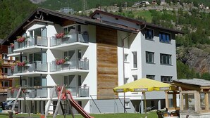 Ein mehrstöckiges Hotel mit Balkonen, einem Spielbereich und Außenmöbeln.