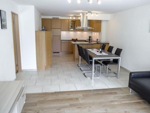 A modern kitchen with wooden cabinets, a central island, and a dining area with a table and chairs.