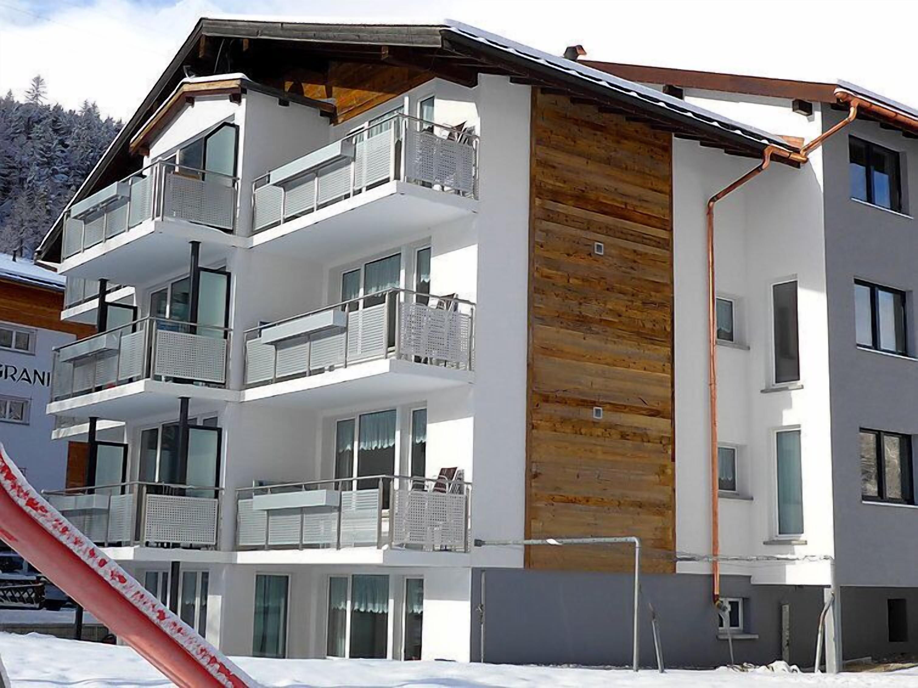 A multi-story building with balconies, large windows, and a wooden accent wall.
