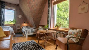 A cozy room with a bed, a sofa, a chair, a small table, and a window with a view of greenery. - Apartment Rekowo by Interhome (Rekowo)