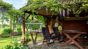 A rustic outdoor seating area with a swing, a wooden table, and chairs under a pergola covered with vines. - Apartment Rekowo by Interhome (Rekowo)