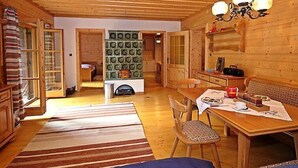 Un intérieur de chalet chaleureux avec un coin repas, des murs en bois, une cheminée et un lustre.