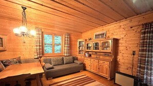 L’intérieur chaleureux d’un chalet comprend une table à manger en bois, un canapé et un coin cuisine avec des placards et un four encastré.
