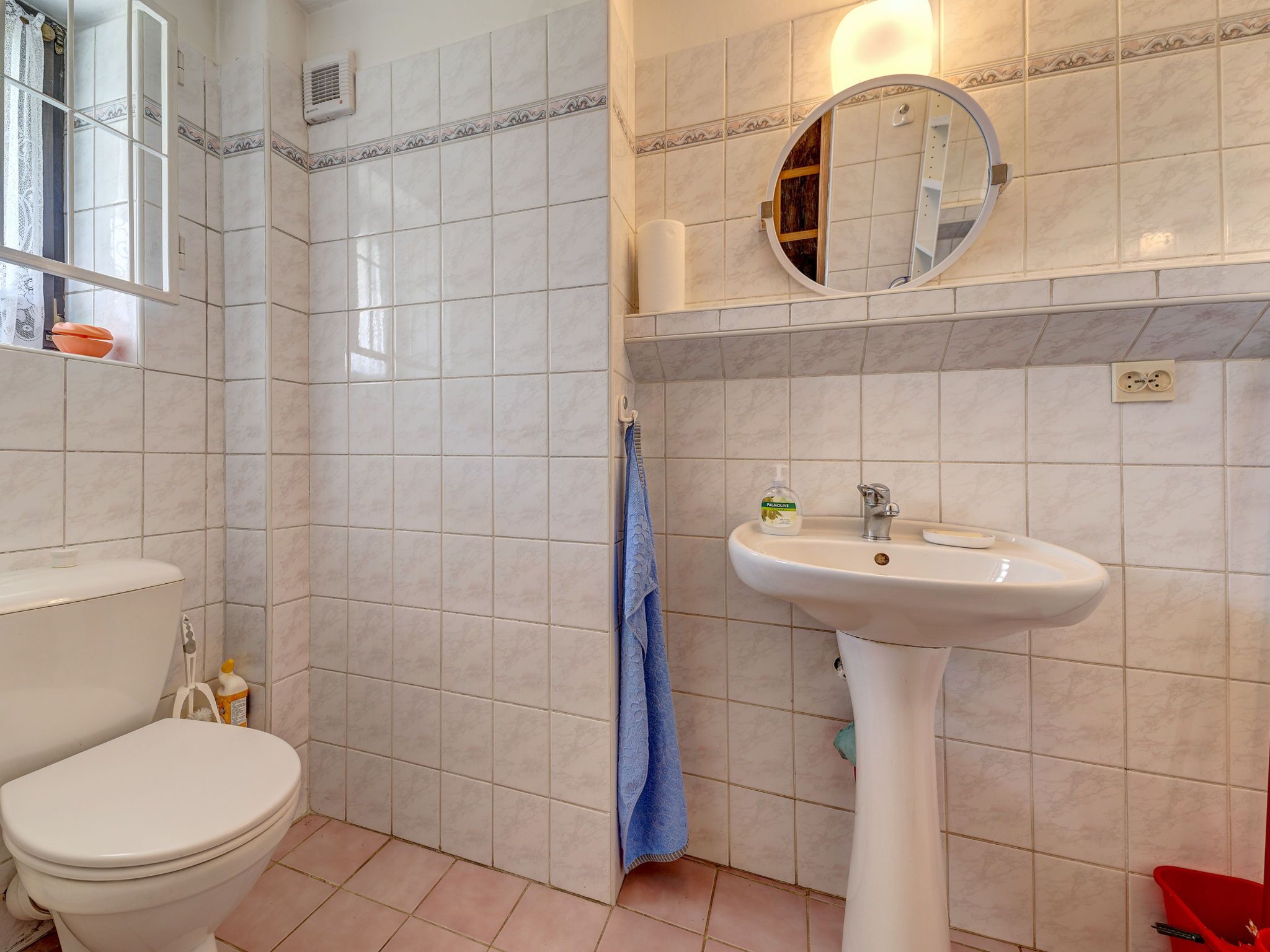 A bathroom with a toilet, sink, and mirror.