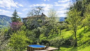 Une maison avec une piscine, entourée d’une végétation luxuriante et de collines.